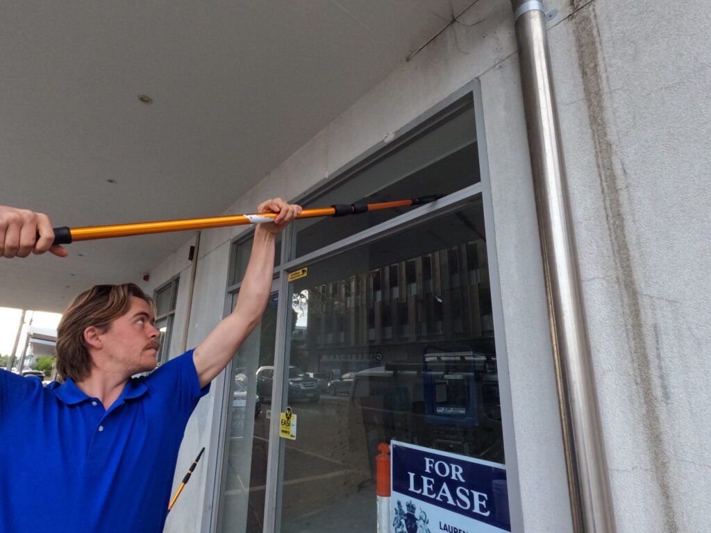 Commercial window cleaner using a extended pole to clean a store front shop.