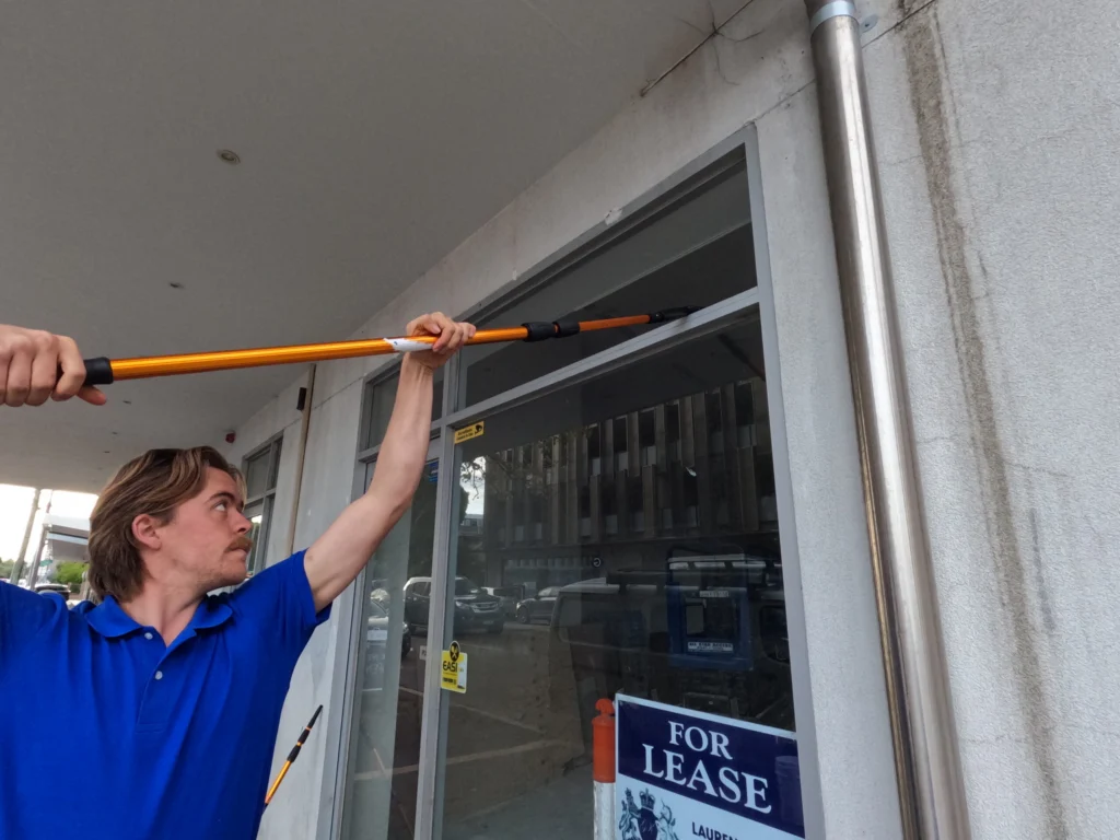 Commercial window cleaner using a extended pole to clean a store front shop.