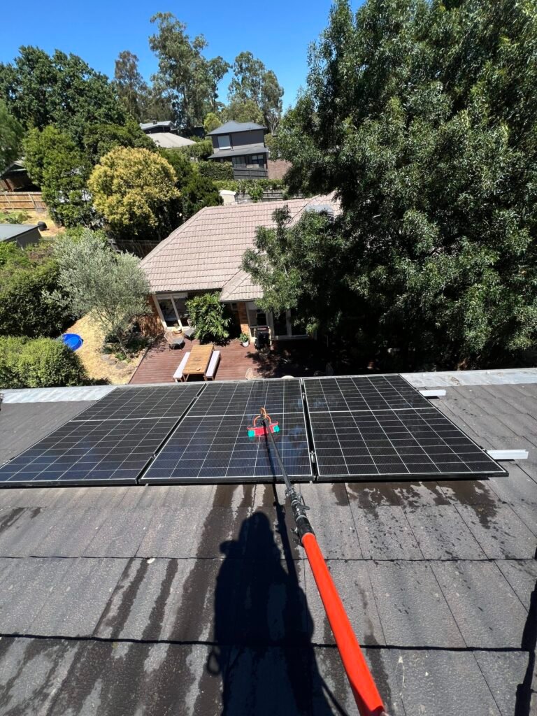 A residental solar panels being cleaned using a water fed pole on the second story.